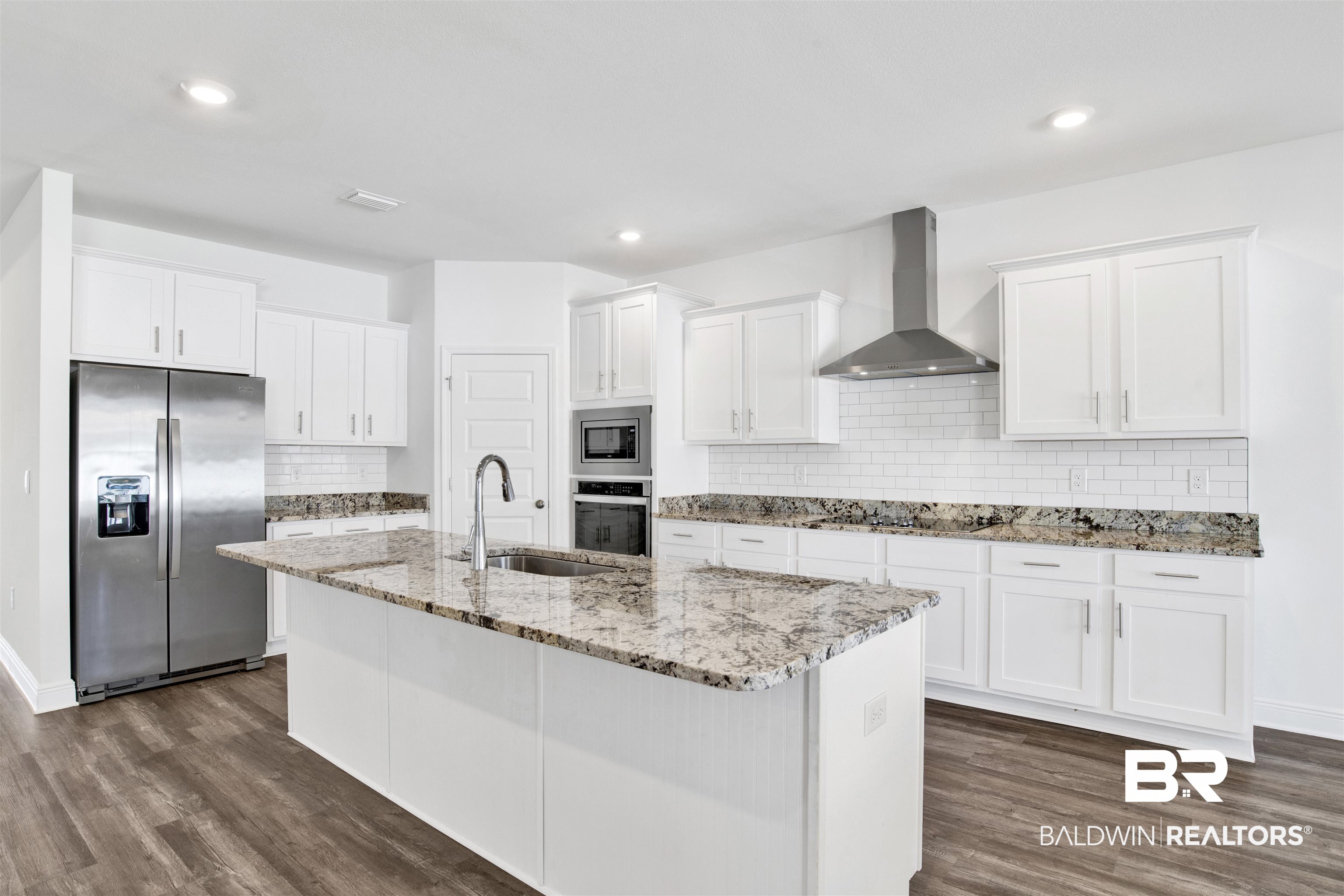 11602 Genuine Risk Circle Daphne, AL 36526 - Photo 10 of 30 Kitchen featuring stainless steel appliances, light stone countertops, white cabinets, wall chimney range hood, and decorative backsplash