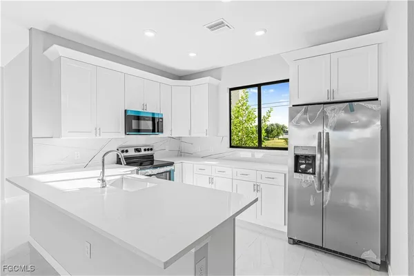 a kitchen with a refrigerator a sink a stove a microwave and cabinets