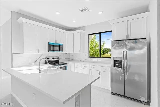a kitchen with a refrigerator a sink a stove a microwave and cabinets