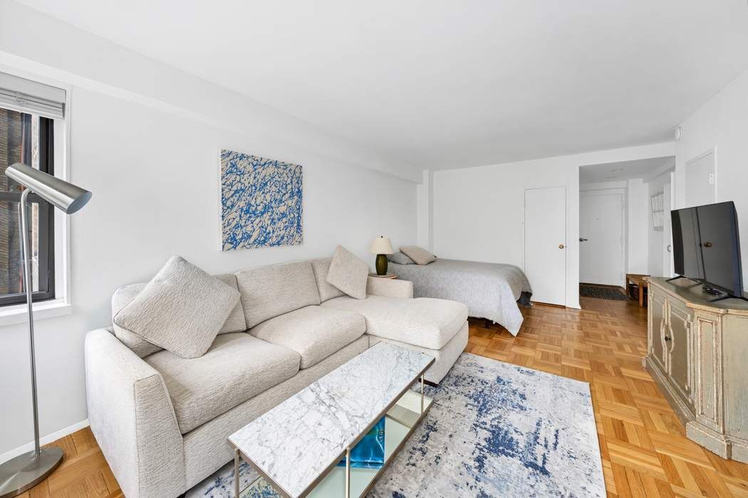 305 East 72nd Street, Unit 5AS Manhattan, NY 10021 - Photo 10 of 11 a living room with furniture a flat screen tv and a refrigerator