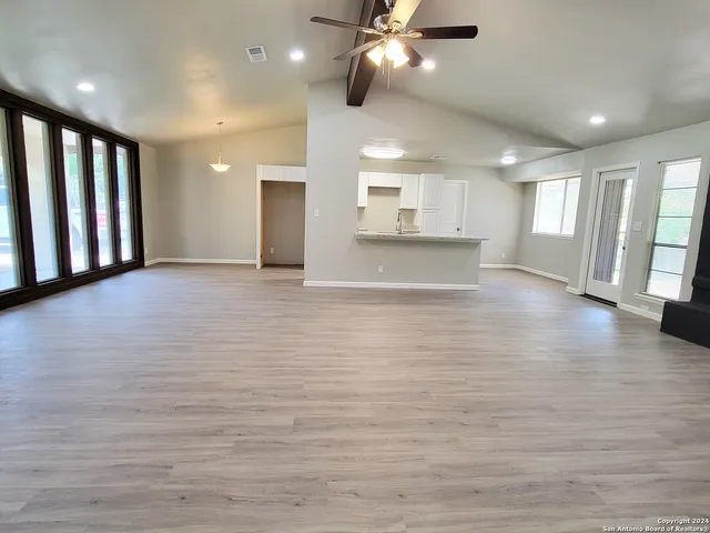 a view of an empty room with window and wooden floor