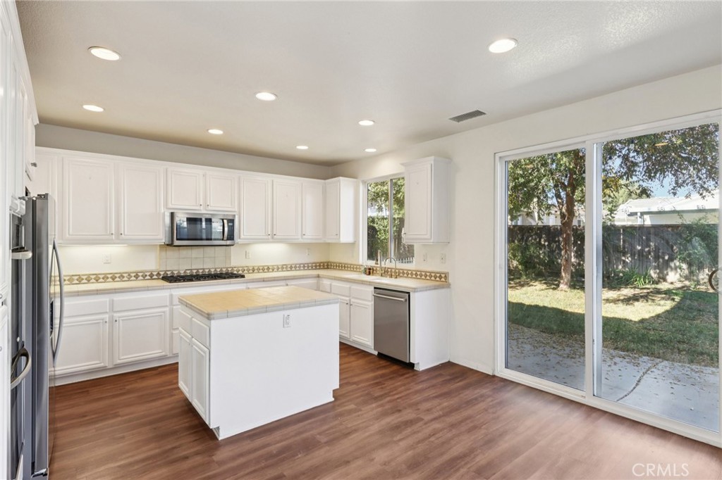 29144 Lighthouse Court Menifee, CA 92585 - Photo 11 of 35 a kitchen with stainless steel appliances granite countertop a refrigerator a sink dishwasher a stove and white countertops with wooden floor