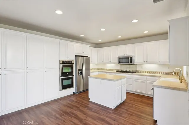 a kitchen with stainless steel appliances granite countertop a refrigerator a stove top oven a sink and dishwasher with wooden floor