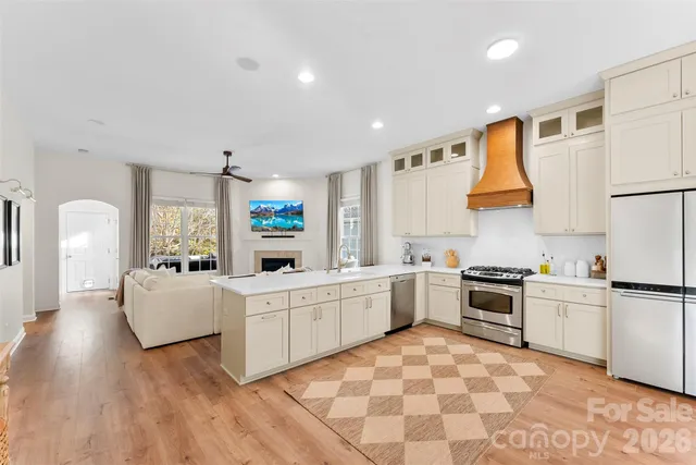 a large white kitchen with a stove a sink dishwasher and a refrigerator with wooden floor