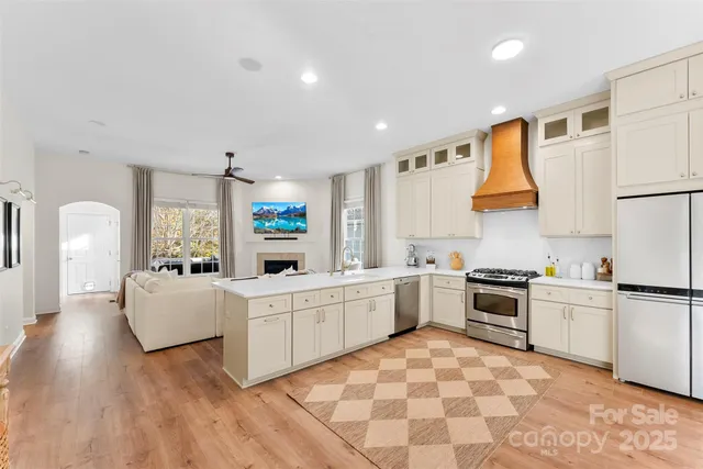 a large white kitchen with a stove a sink dishwasher and a refrigerator with white cabinets