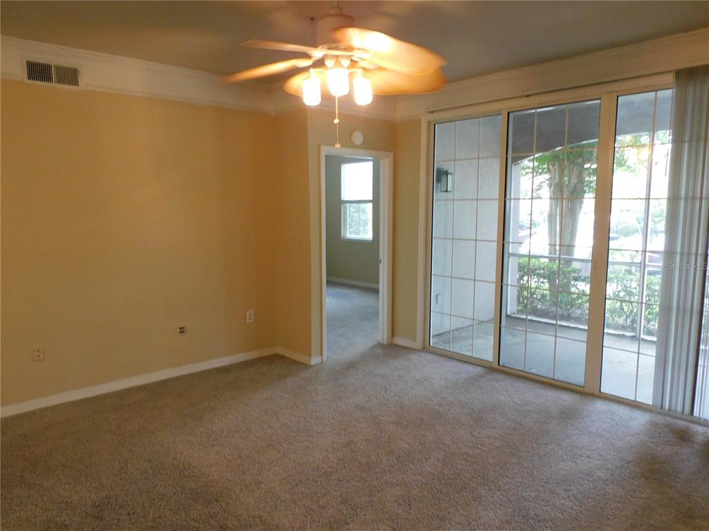 3480 Soho Street, Unit 101 Orlando, FL 32835 - Photo 11 of 29 a view of an empty room with chandelier fan and a large window