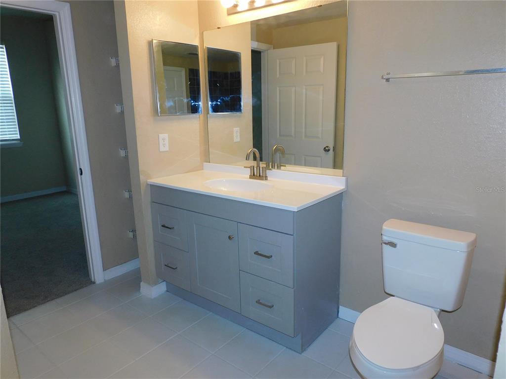 3480 Soho Street, Unit 101 Orlando, FL 32835 - Photo 16 of 29 a bathroom with a toilet a sink and mirror