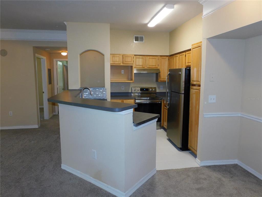 3480 Soho Street, Unit 101 Orlando, FL 32835 - Photo 3 of 29 a kitchen with kitchen island a counter top space cabinets and stainless steel appliances
