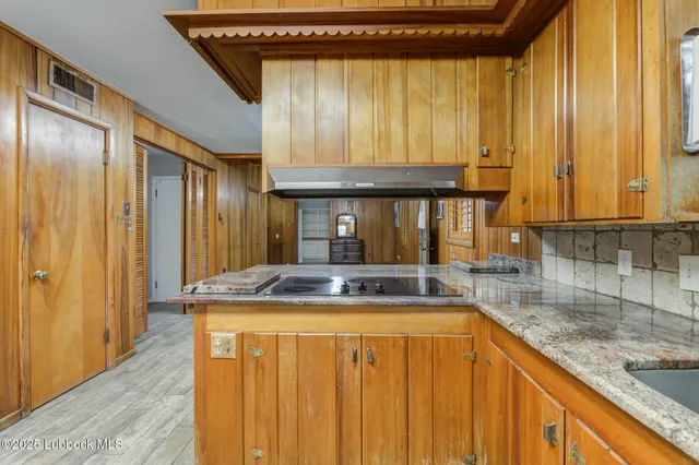 an empty room with a chandelier fan and windows