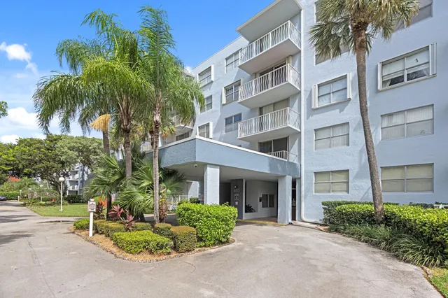 a front view of multi story residential apartment building with yard and green space