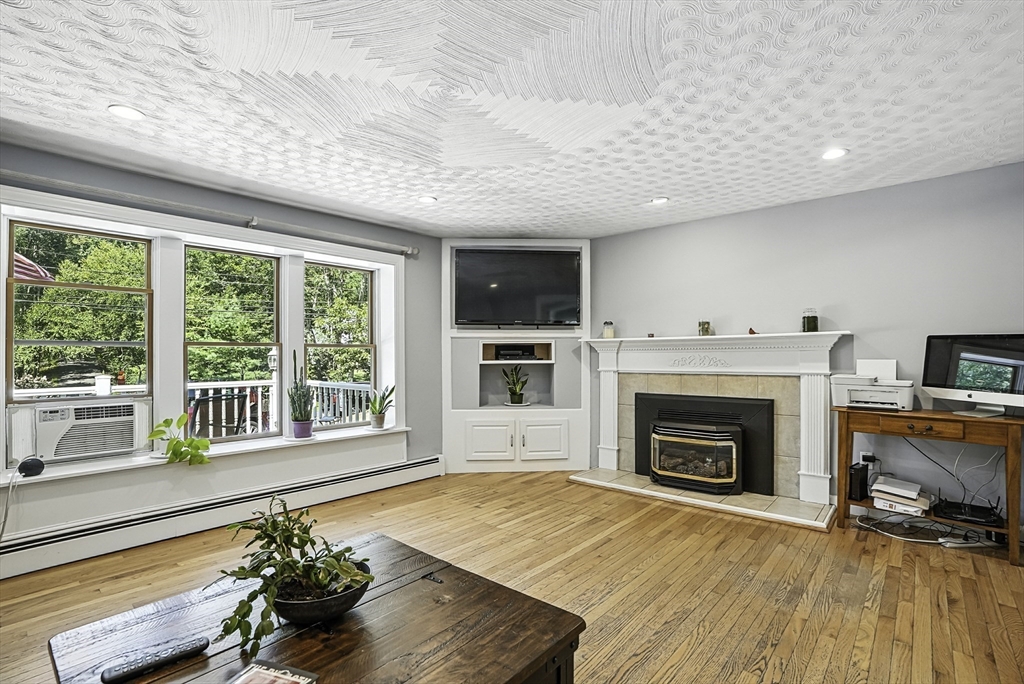 334 Mendon Road Northbridge, MA 01534 - Photo 6 of 31 a living room with a fireplace and a floor to ceiling window