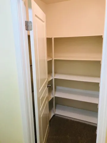 a view of an empty room with a chandelier fan
