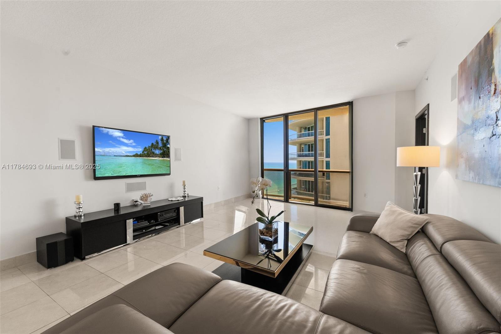 16275 Collins Avenue, Unit 2202 Sunny Isles Beach, FL 33160 - Photo 3 of 23 a living room with furniture and a flat screen tv