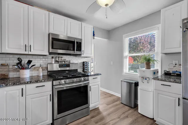 a kitchen with stainless steel appliances granite countertop a sink dishwasher a stove and a microwave oven with cabinets
