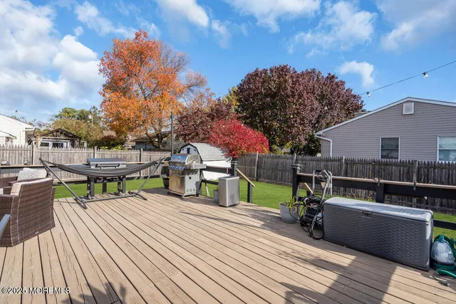 a view of house with deck outdoor seating and trees in the background