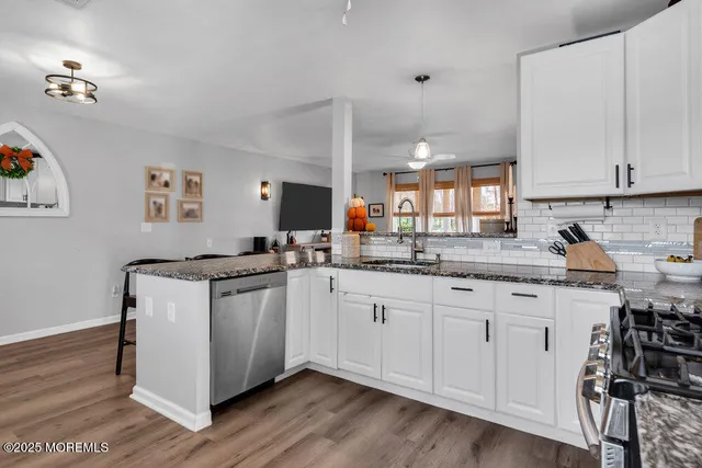 a kitchen with granite countertop a sink cabinets and wooden floor