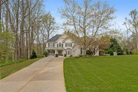 a front view of a house with a garden and trees