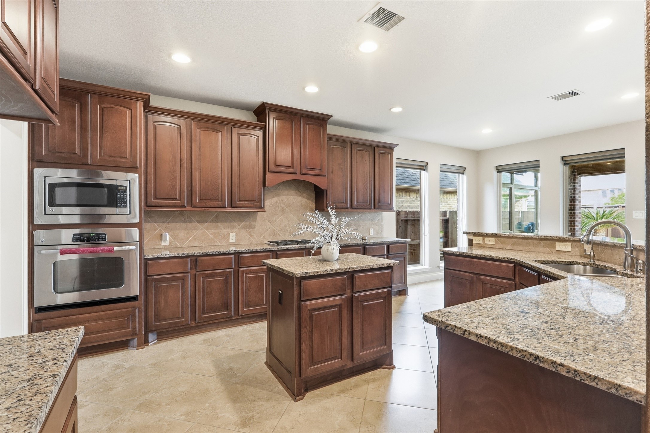 4130 Clover Ridge Lane Sugar Land, TX 77479 - Photo 8 of 48 This kitchen features elegant dark wood cabinetry, granite countertops, and a central island. It includes stainless steel appliances and ample natural light from large windows.