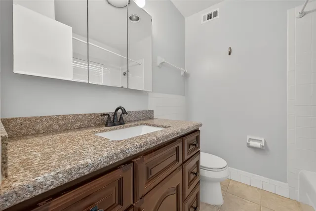 a bathroom with a granite countertop sink and toilet