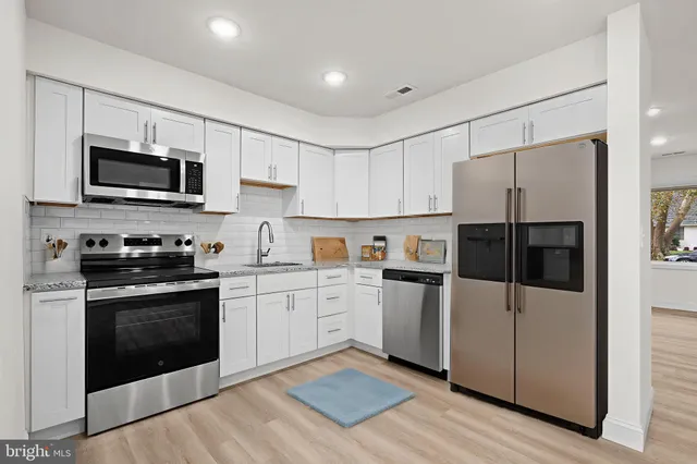 a kitchen with cabinets stainless steel appliances and wooden floor