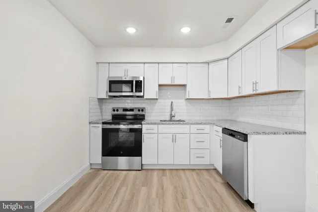 a kitchen with stainless steel appliances granite countertop a stove a sink and a microwave