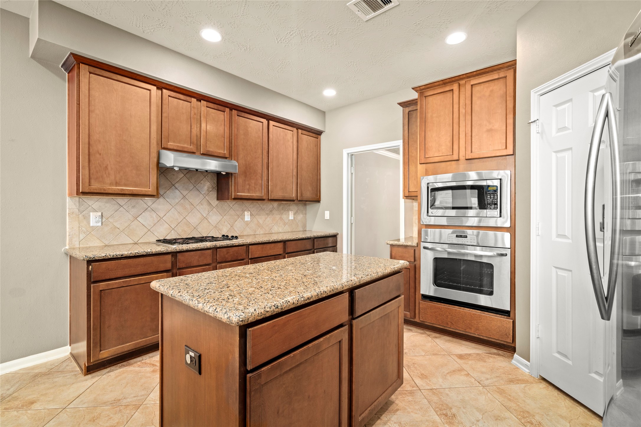 5307 Amber Sky Lane Rosharon, TX 77583 - Photo 19 of 50 Rich wood cabinetry, granite counters, and a spacious center island define this exceptional kitchen, thoughtfully designed as the true heart of the home.