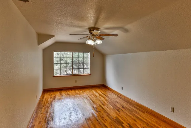 a view of an empty room with a window and wooden floor