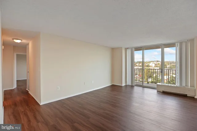a view of an empty room with wooden floor and a window