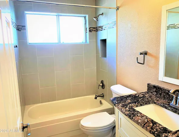 a bathroom with a granite countertop bathtub shower sink vanity and a toilet