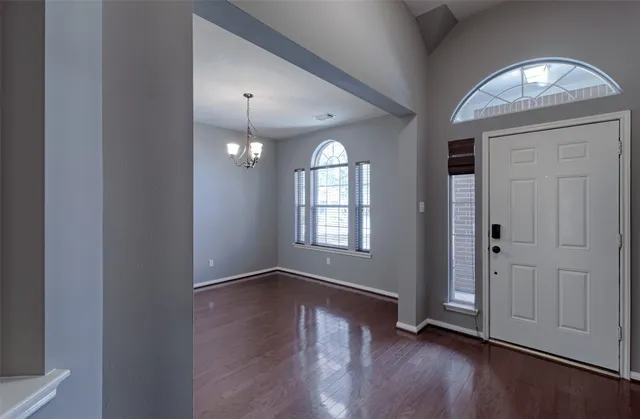 an empty room with wooden floor mirror and windows