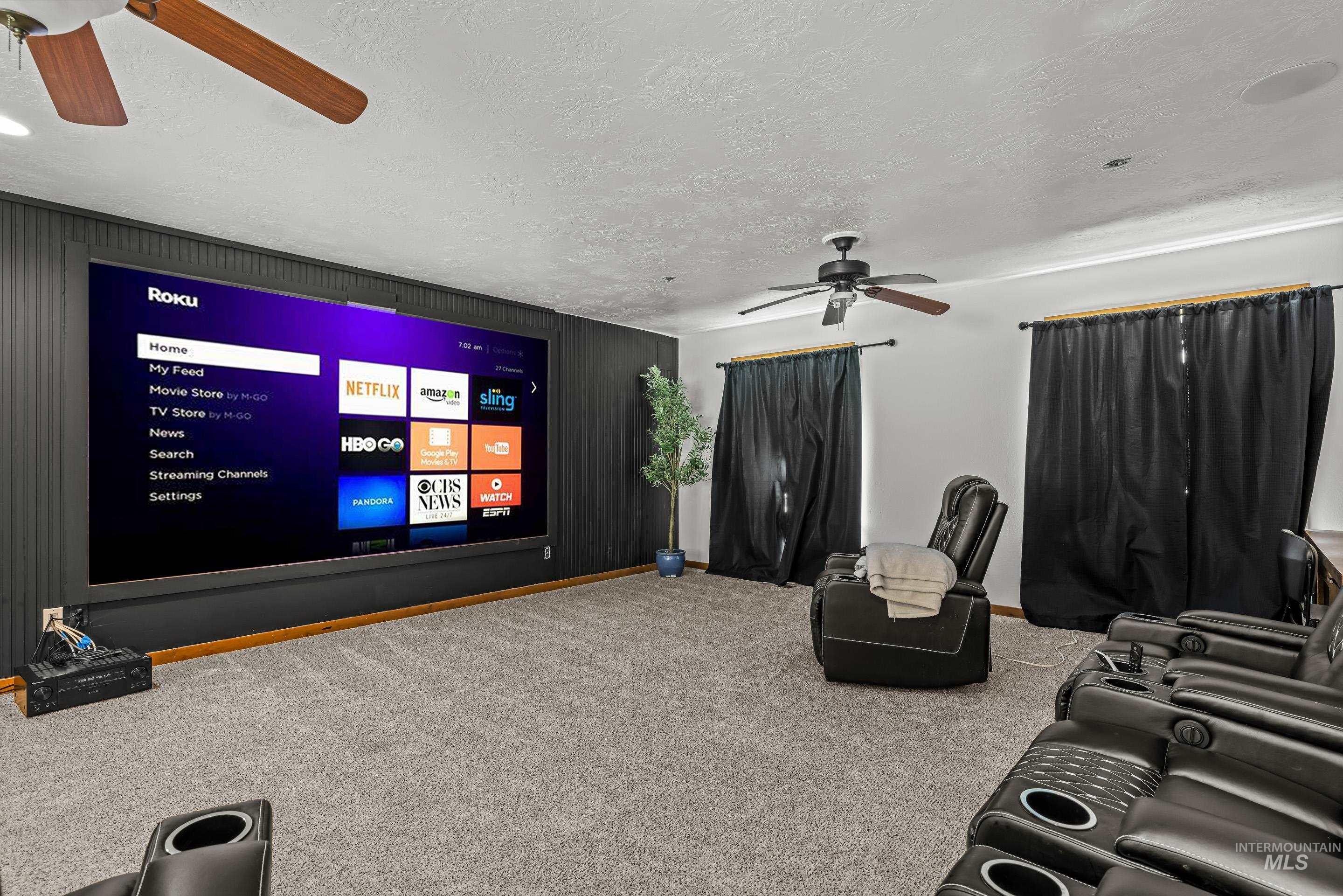 92 Cruickshank Road Horseshoe Bend, ID 83629 - Photo 39 of 50 Dedicated media room featuring a large projection screen, dark paneled accent wall, and ceiling-mounted fans