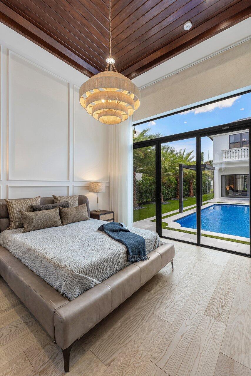 17709 Circle Pond Court Boca Raton, FL 33496 - Photo 38 of 50 a spacious bedroom with a large bed and a chandelier