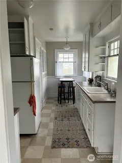 a kitchen with stainless steel appliances granite countertop a refrigerator a sink dishwasher a dining table and chairs with wooden floor