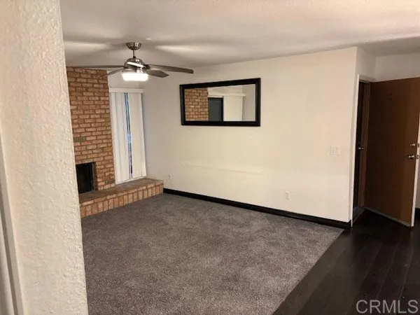 an empty room with wooden floor chandelier fan and windows