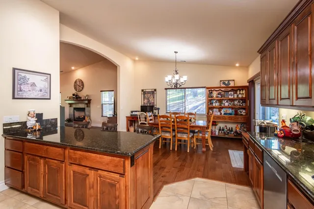 a kitchen with stainless steel appliances wooden floors wooden cabinets a refrigerator and a stove top oven
