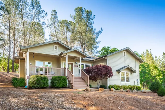 a view of a white house with a yard and large tree