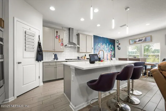 a kitchen with stainless steel appliances kitchen island a table chairs sink and cabinets