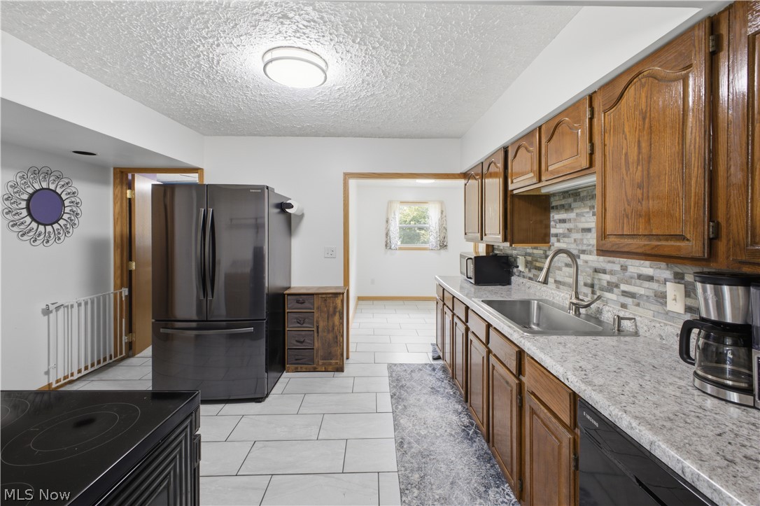 1057 Center Road Clinton, OH 44216 - Photo 10 of 24 Kitchen featuring wood cabinetry, light-toned countertops, a mosaic tile backsplash, and a stainless steel sink with a gooseneck faucet