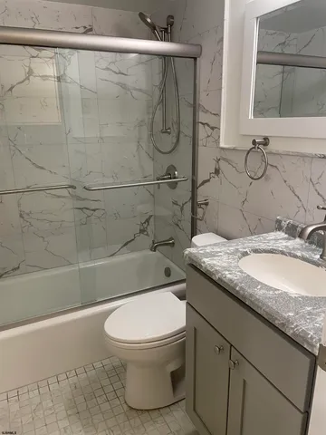 a bathroom with a granite countertop sink a mirror and shower