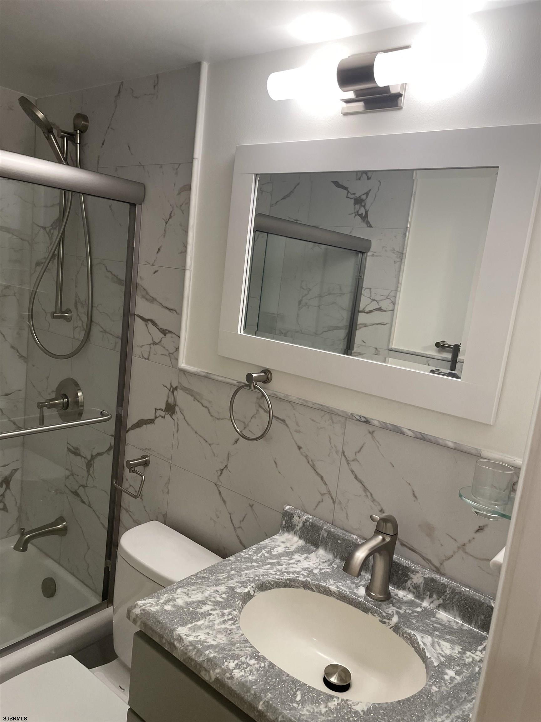 1600 Atlantic Avenue, Unit 47 Longport, NJ 08403 - Photo 12 of 12 a bathroom with a granite countertop sink a mirror and shower