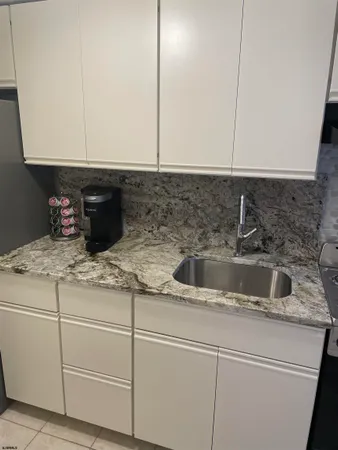 a kitchen with granite countertop white cabinets and a sink