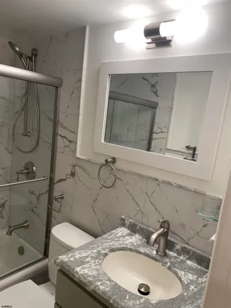 a bathroom with a granite countertop sink a mirror and shower