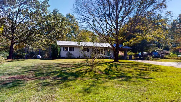 a view of a house with a large tree and a yard