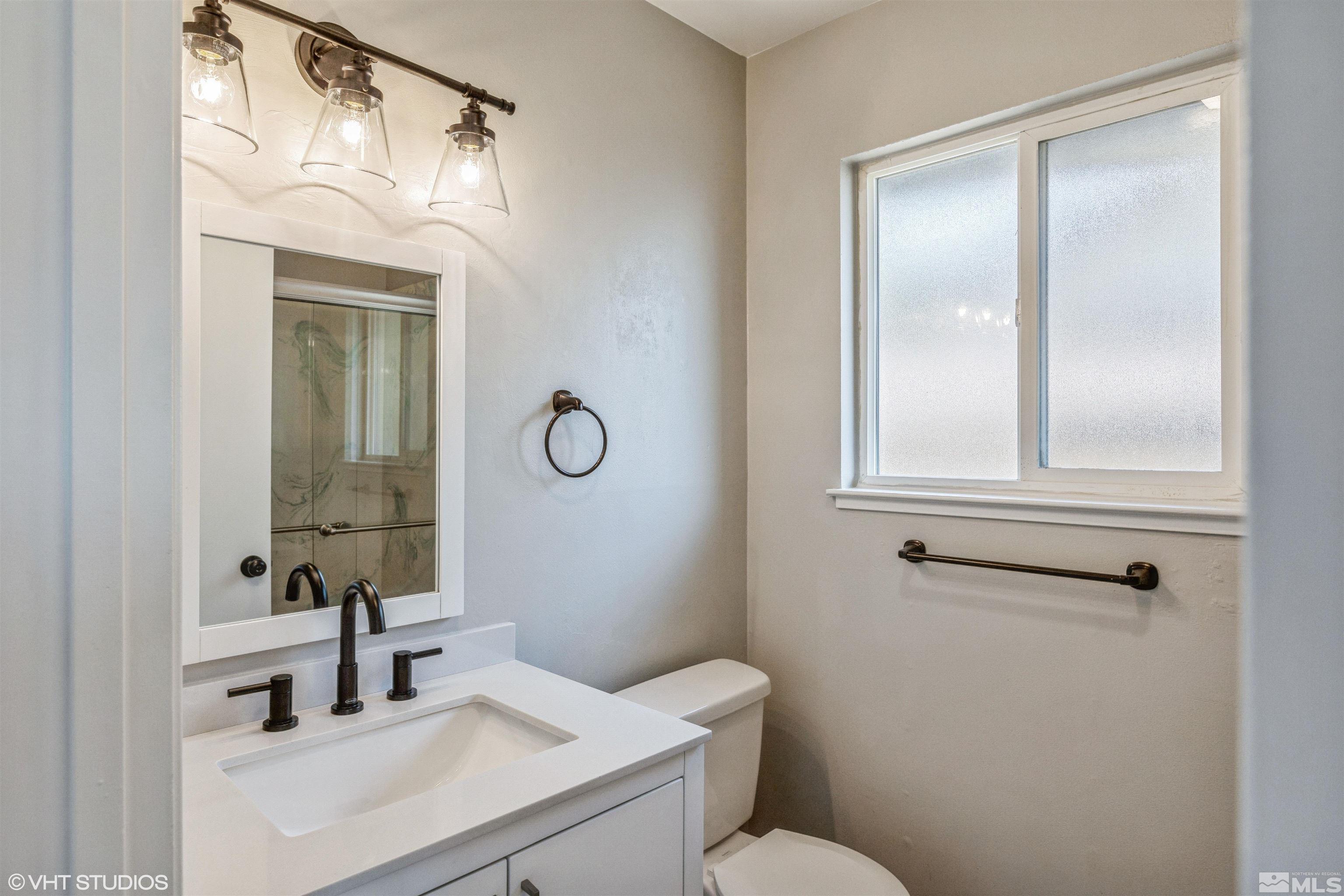 1930 Stardust Street Reno, NV 89503 - Photo 13 of 15 a bathroom with a toilet sink vanity and mirror