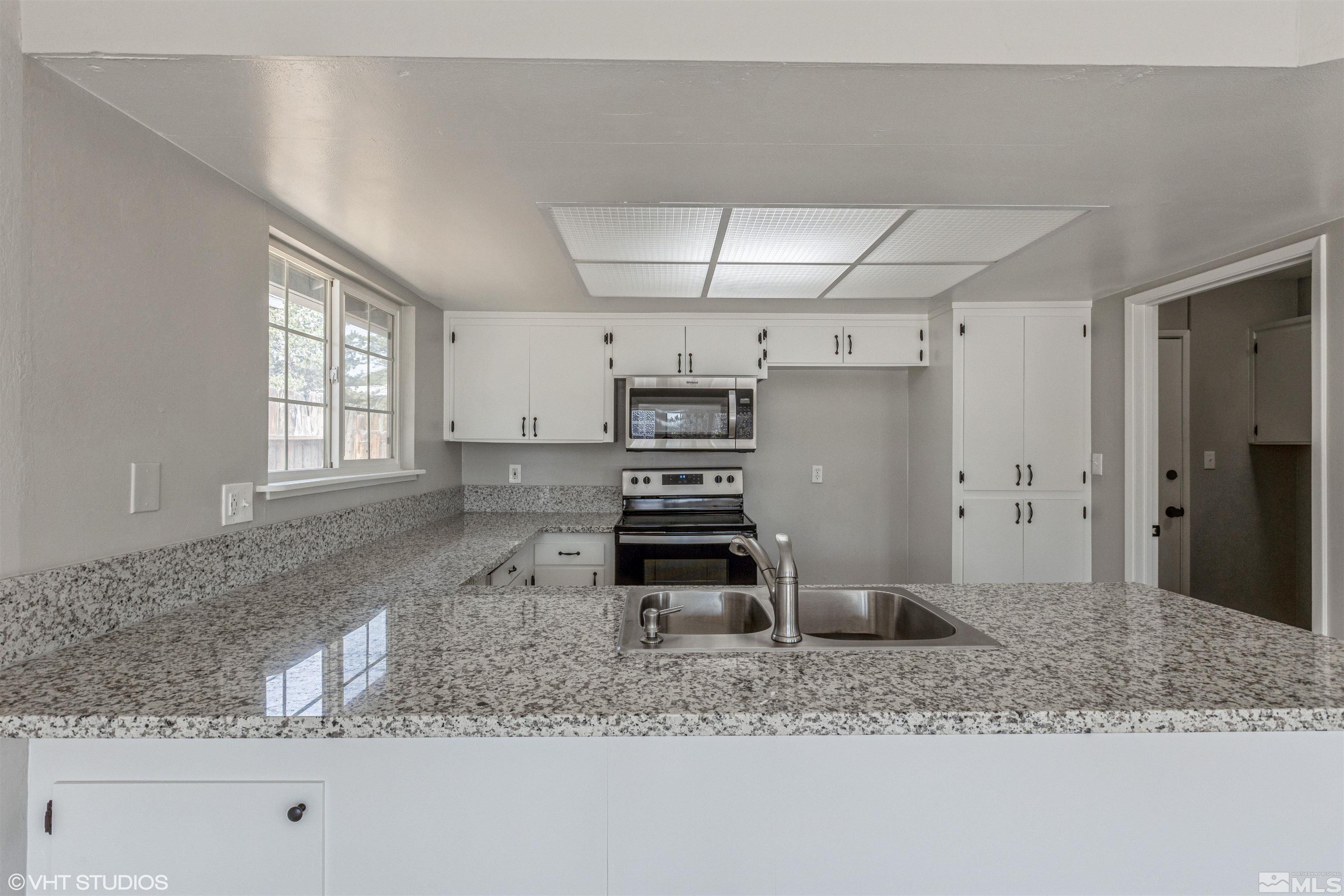 1930 Stardust Street Reno, NV 89503 - Photo 6 of 15 a kitchen with stainless steel appliances kitchen island granite countertop a sink stove and granite counter top