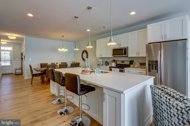 a kitchen with kitchen island stainless steel appliances a stove a sink a oven a dining table and chairs