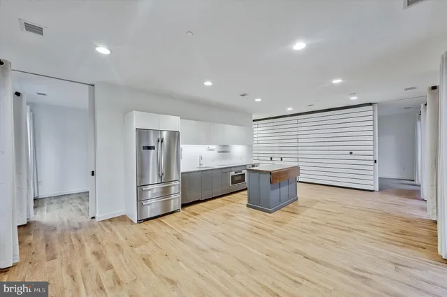 a view of an empty room with wooden floor and a bathroom