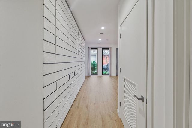 a view of an empty room with wooden floor and a bathroom
