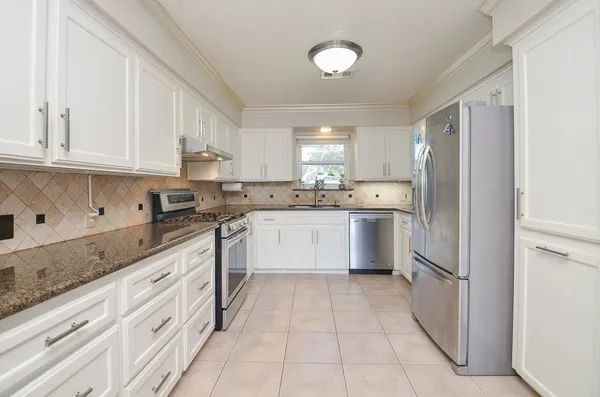 a kitchen with white cabinets stainless steel appliances and a window