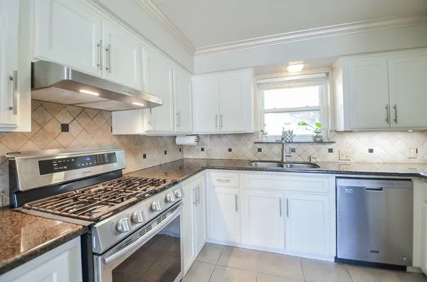a kitchen with white cabinets appliances and a sink